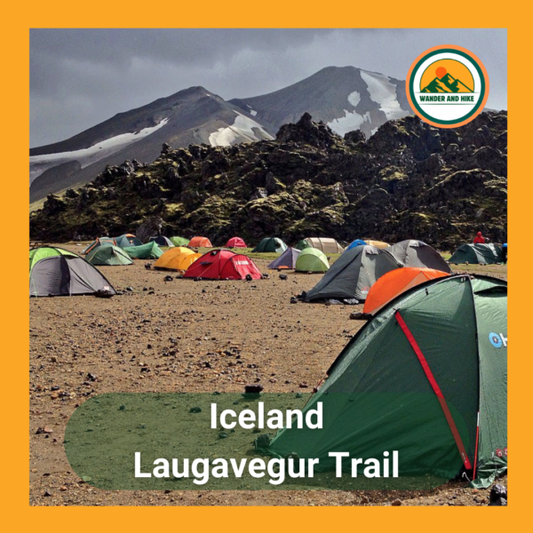 Colorful tents at a busy campsite on Iceland's Laugavegur Trail, set against rugged, volcanic mountains with snow patches. Text 'Iceland Laugavegur Trail' and Wander and Hike logo included.